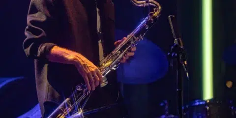 Musicien à lunettes jouant du saxophone sur scène.