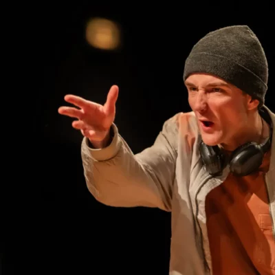 Homme en bonnet gris criant avec un geste expressif.